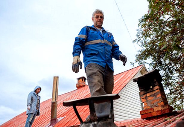 Two crewmen checking a roof between chimneys